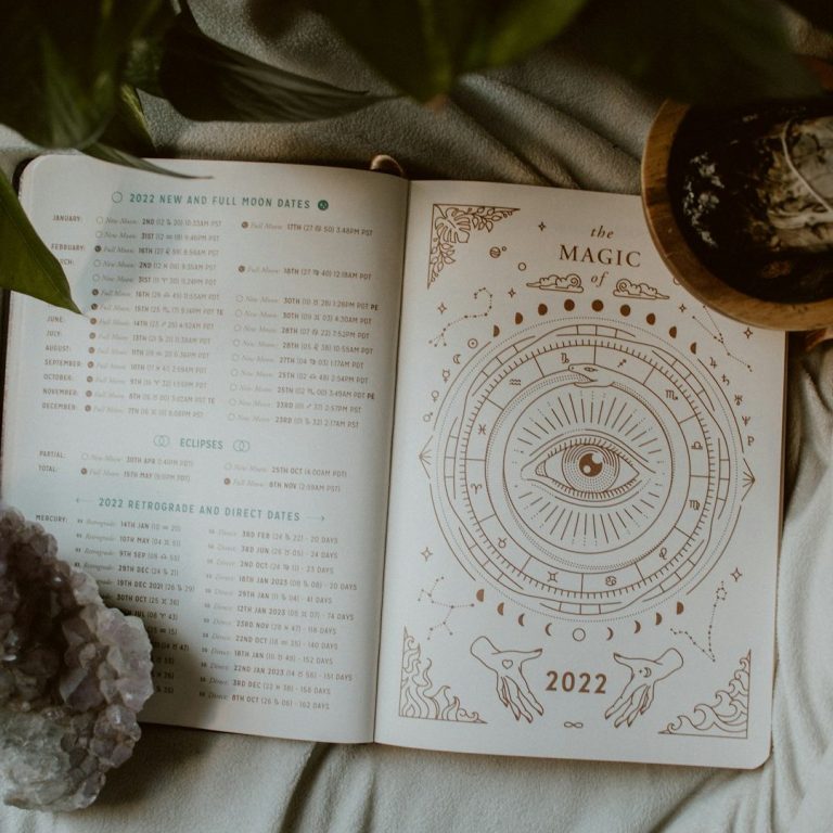 Astrolojik Semboller ve Notlar Açık bir not defteri üzerindeki notlara ve sembollere işaret eden eller, mumlarla çevrili